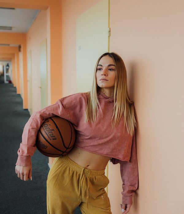 Woman in a light, comfortable outfit performing a gentle stretching movement in a sunny room.